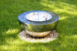 reflective surface bowl style pondless water feature set in a green lawn